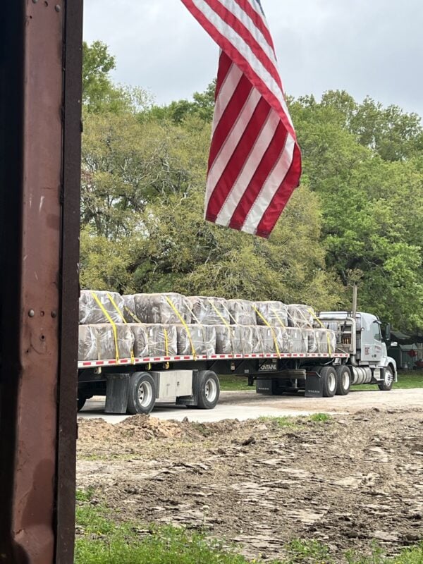 A truck with bales of hay on the back of it.