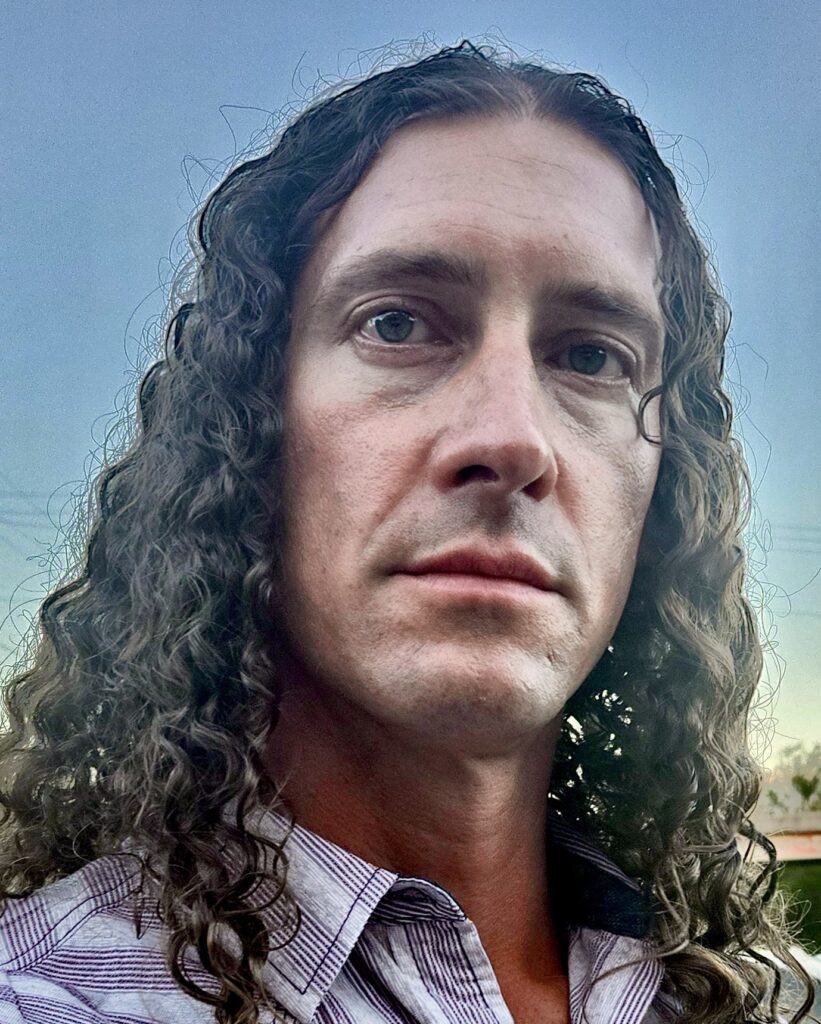 A man with long hair and wearing a tie.